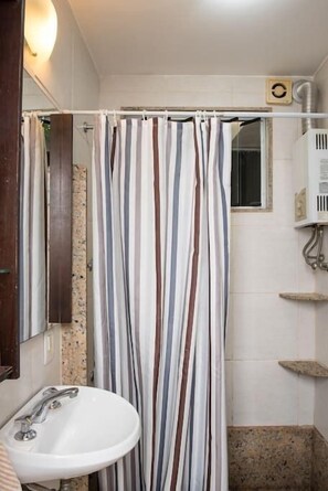 A bathroom with a striped shower curtain, a sink, and a mirror.