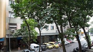 Straßenansicht mit parkenden Autos, Bäumen und Gebäuden.