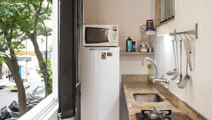 Eine schmale Küche mit Kühlschrank, Herd und Spüle.