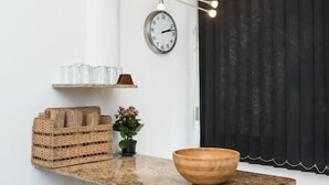 Eine Küche mit einer Holztresen, Hockern, einer Uhr und einem Fenster mit Vorhang.