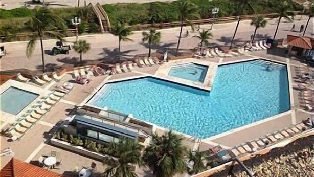 A pool area with multiple swimming pools, lounge chairs, and palm trees.