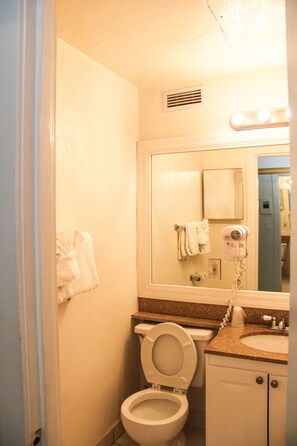 A bathroom with a toilet, sink, and a hairdryer on the counter. - Hollywood Beach Resort- Stylish Large Studio (Hollywood)