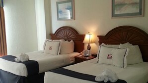 A hotel room with two beds, each with a headboard, a nightstand with a lamp, and a painting on the wall.
