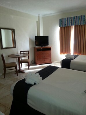 A hotel room with two beds, a desk with a chair, a television on a dresser, and a window with curtains. - Hollywood Beach Resort-beautiful Studio Sleeps 4 (Hollywood)