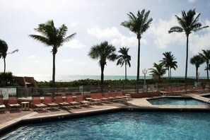 A pool area with lounge chairs and palm trees, overlooking a beach. - Hollywood Beach Resort-spacious Ocean View Studio (Hollywood)