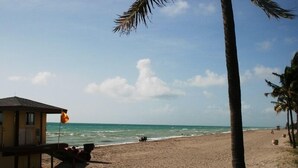 Ein Strand mit einer Rettungswache, Palmen und blauem Himmel.