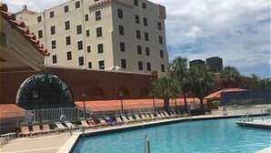 A hotel pool area with a large rectangular pool, lounge chairs, and a building with multiple floors and balconies. - Hollywood Beach Resort- One Bedroom Ocean View (Hollywood)