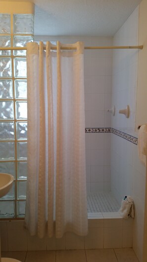 A bathroom with a shower, a glass door, and a tiled floor.