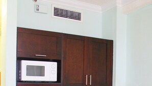 A compact kitchen with dark wooden cabinets, a white microwave, a coffee maker, and a dishwasher. - Hollywood Beach Resort - Renovated Large Studio (Hollywood)