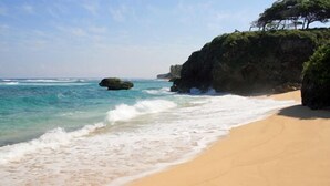 A beach with clear turquoise water, a sandy shore, and a rocky cliff with vegetation. - Family Oriented - Private Beach & Horse Stables - Ocean, Pool, & Hot Tub (Cabrera)
