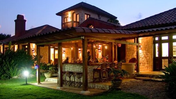 A two-story house with a covered patio area, stone walls, and a chimney. - Family Oriented - Private Beach & Horse Stables - Ocean, Pool, & Hot Tub (Cabrera)