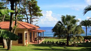 A house with a red roof, a covered porch, and a view of the ocean. - Villa Cabino (Cabrera)
