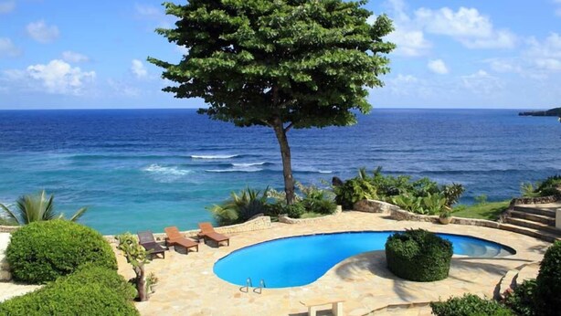 A pool area with a view of the ocean, surrounded by greenery and a tree. - Villa Cabino (Cabrera)