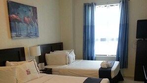 Een hotelkamer met twee bedden, een schilderij aan de muur, een raam met gordijnen en een televisie.
