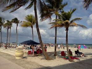 Ein Strand mit Palmen, Liegestühlen und Sonnenschirmen.