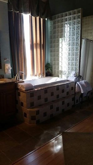 Une salle de bain avec une baignoire, un lavabo et une fenêtre avec des rideaux.