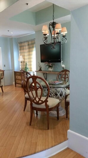 A dining area with wooden chairs and a glass table, a television mounted on the wall, and a chandelier. - Hollywood Beach Resort-tower Suite (Hollywood)