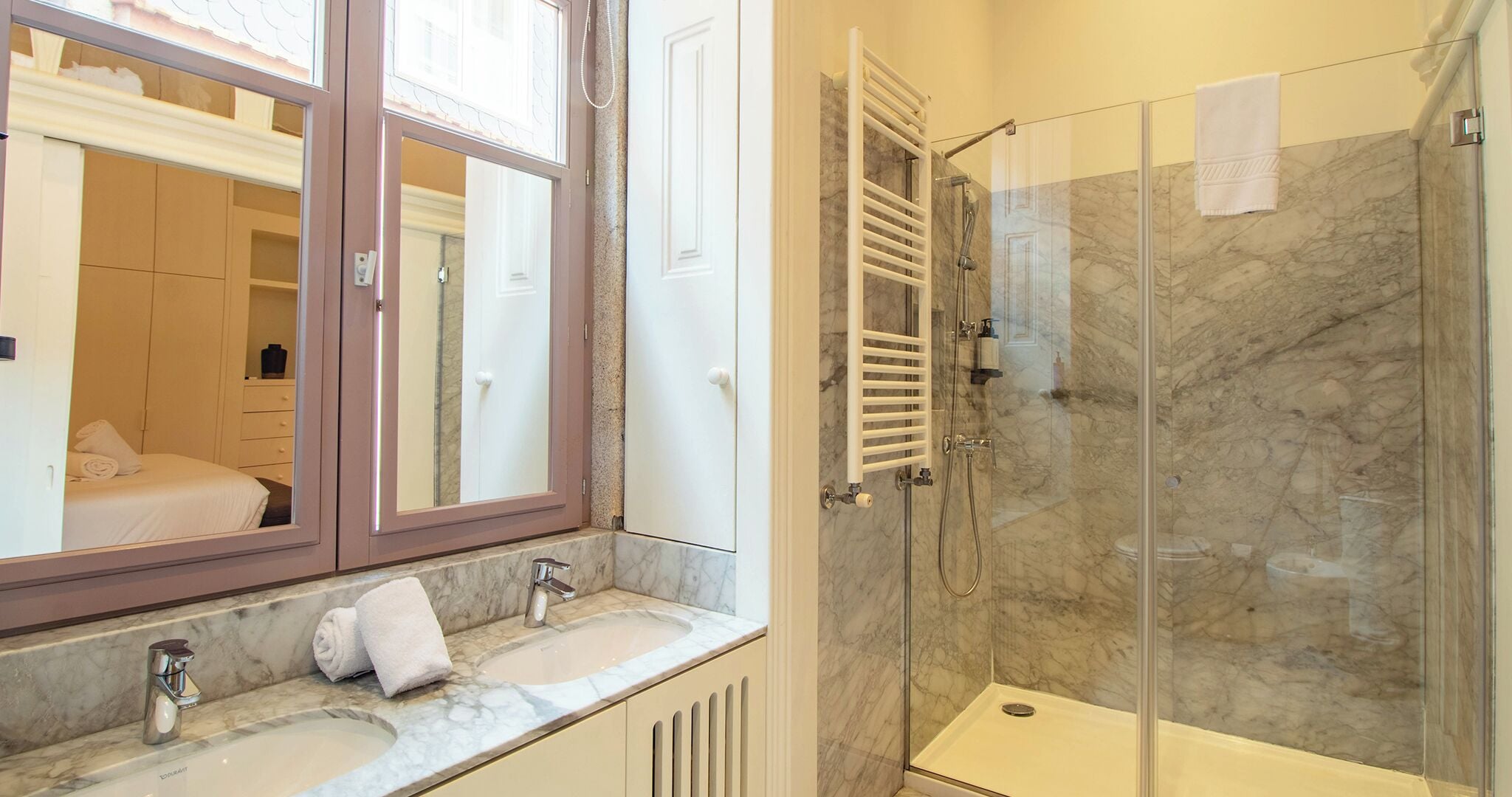 A bathroom with two sinks, a glass shower enclosure, and a large mirror.
