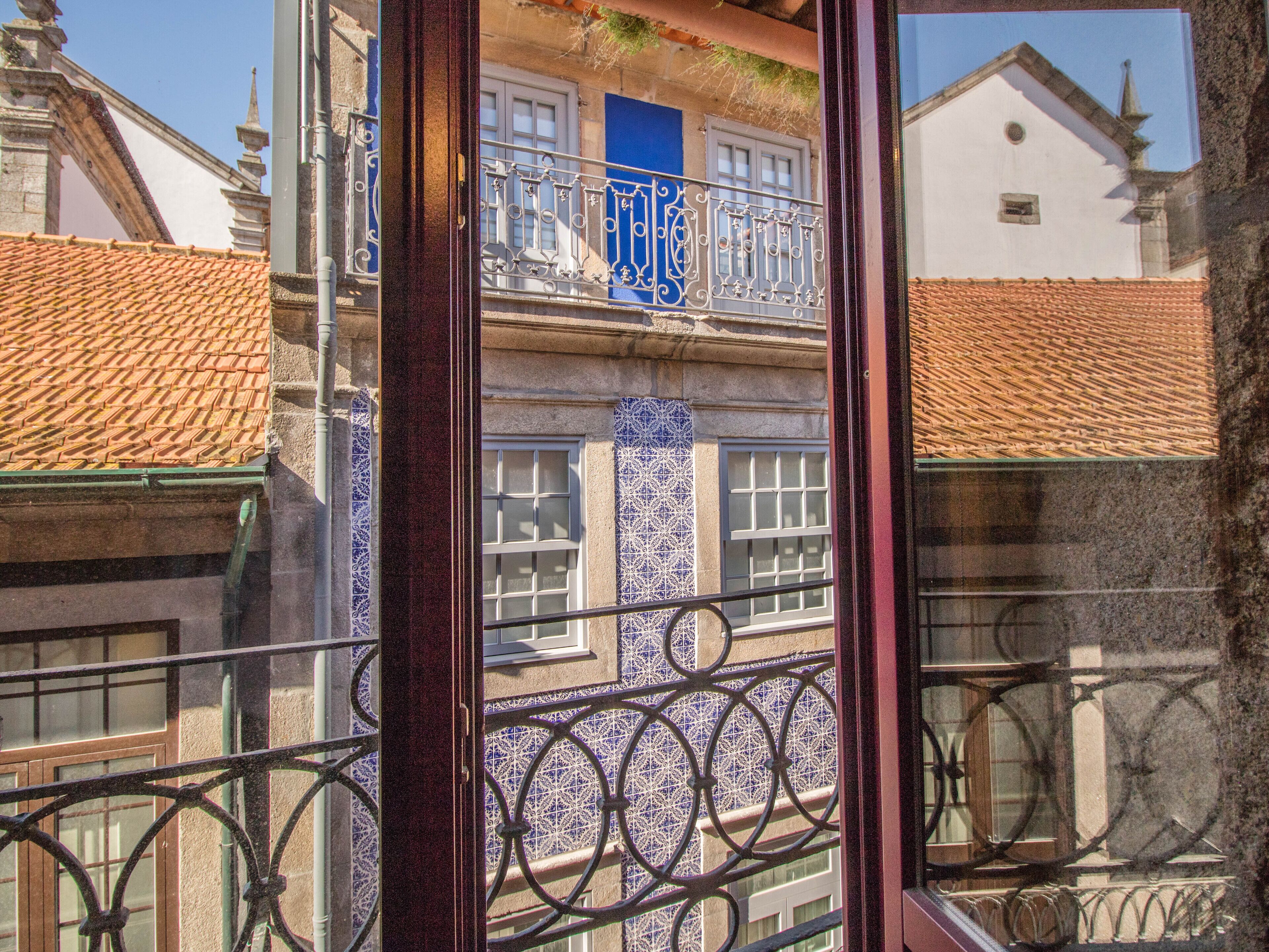 A building with a blue window and a balcony with ornate metal railings.