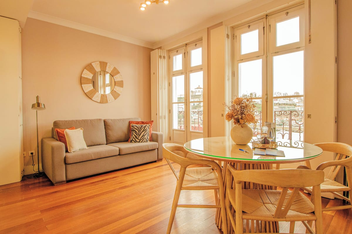 A living room with a sofa, a round glass table, and wicker chairs.