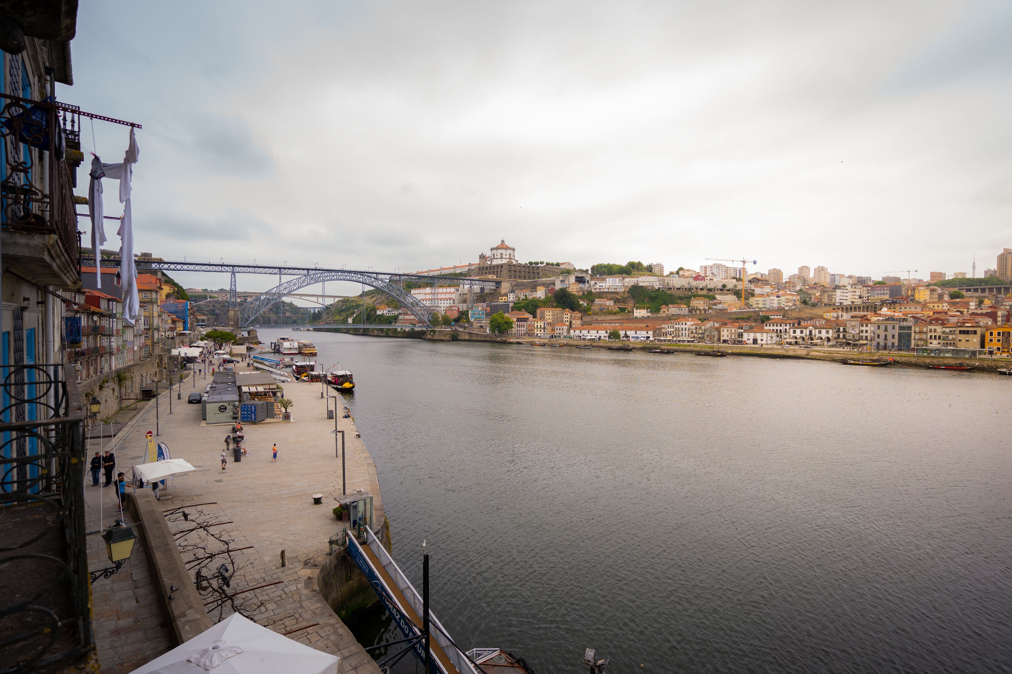 Eine Uferpromenade mit einer Brücke, Gebäuden und Blick auf die Stadt.