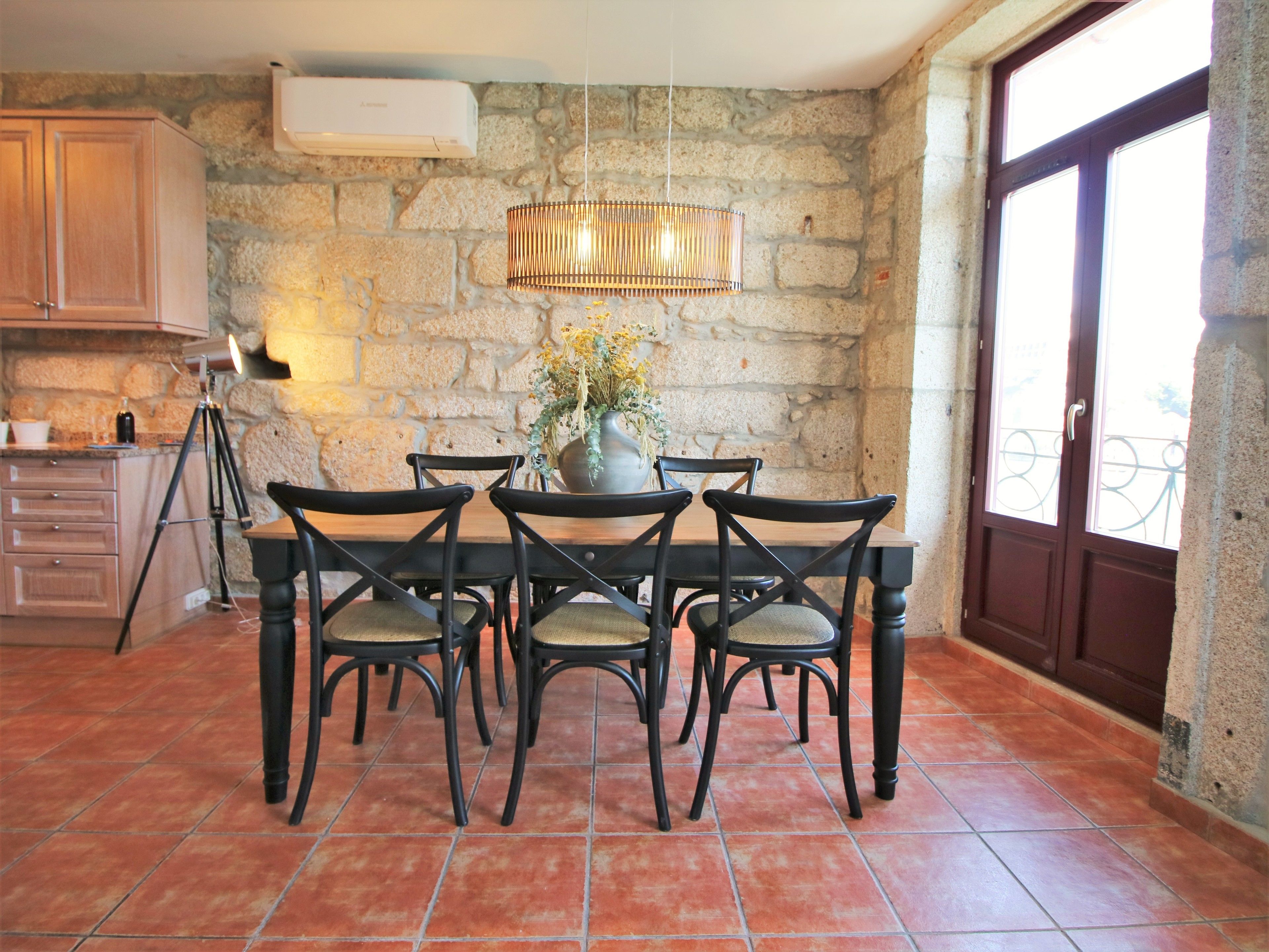 Un comedor con pared de piedra, una mesa de madera y sillas.
