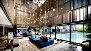A modern lobby with a pool view, marble flooring, and a seating area with a blue sofa. - The Deck Patong (Patong)