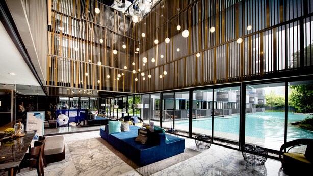 Un lobby moderno con vista a la piscina, pisos de mármol y una zona de estar con un sofá azul.