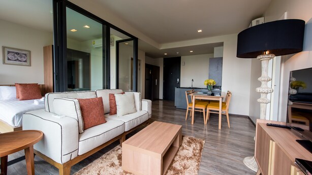A modern living room with a sofa, coffee table, and a dining area with a table and chairs. - The Deck Patong (Patong)
