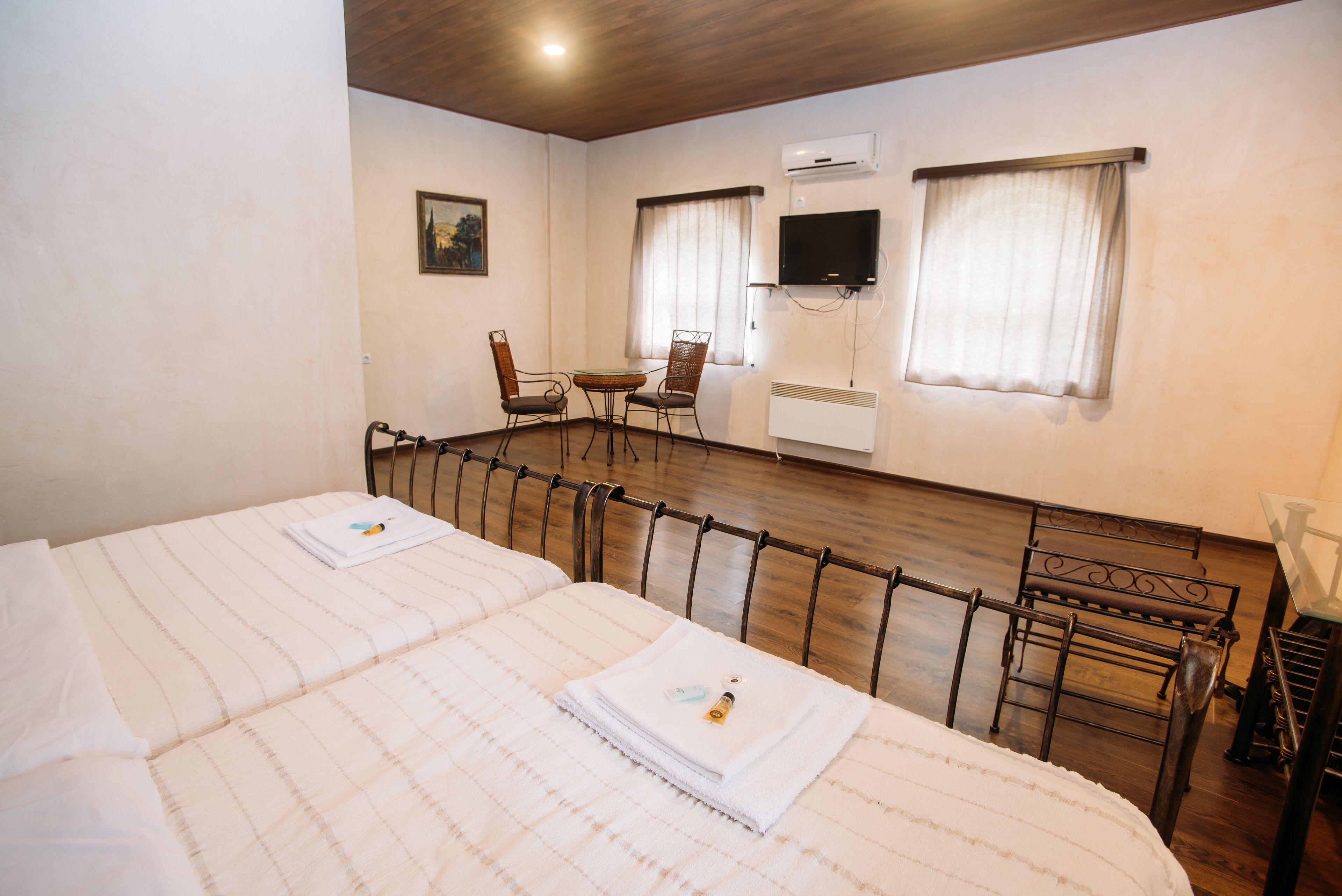 Habitación de hotel con dos camas, una mesita, una silla, televisión y aire acondicionado.