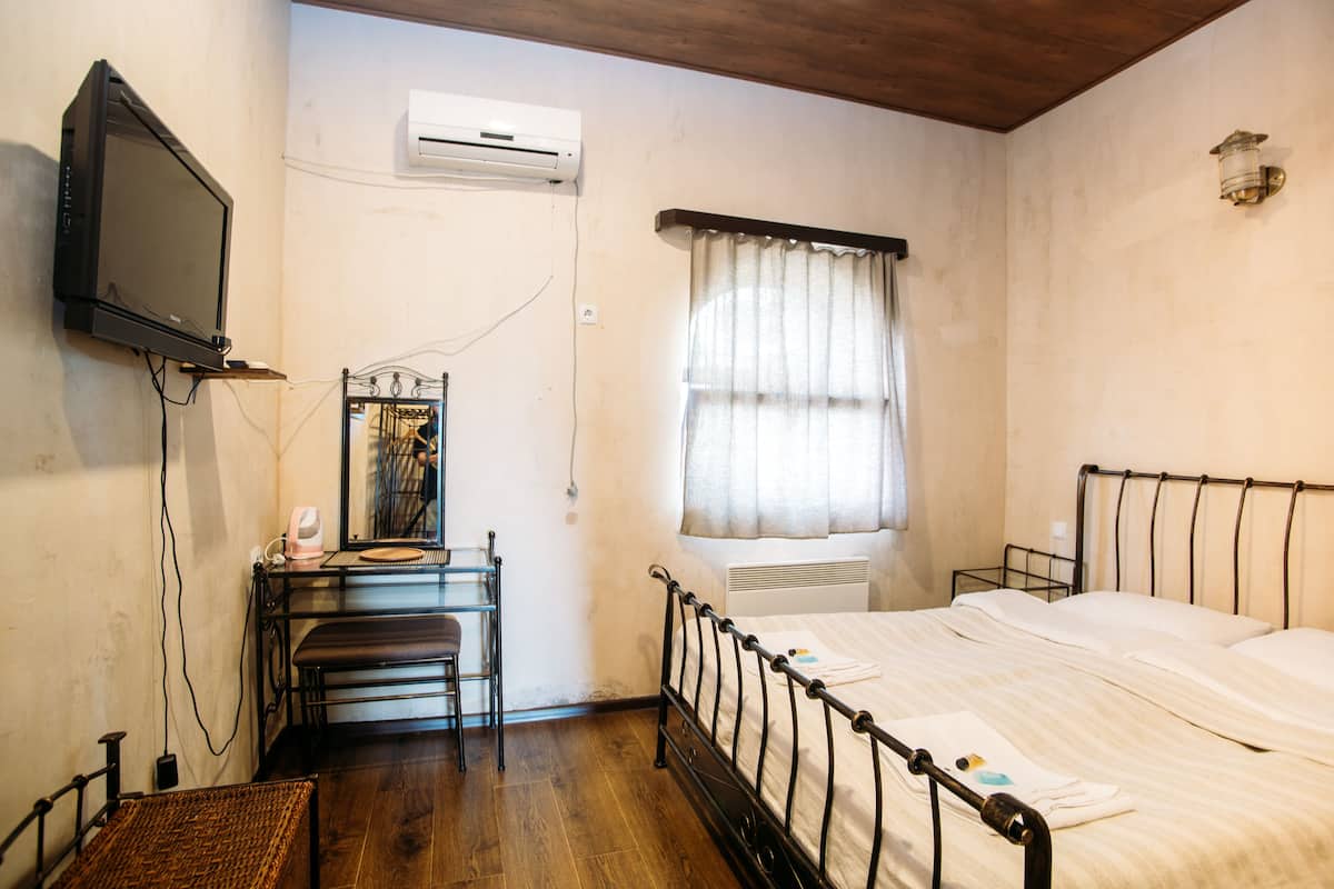 Un dormitorio con cama, escritorio, silla, televisor y aire acondicionado.