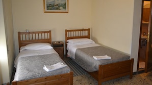 A room with two wooden beds, a small bedside table, a nightstand, and a framed picture on the wall. - Albergo Abruzzese (Riano)