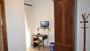 A room with a wooden wardrobe, a desk with a computer, a television, and a coat stand. - Albergo Abruzzese (Riano)