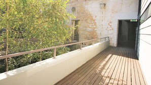 A wooden deck with a metal railing, a stone wall, and a tree in the background. - LUXURY VIEWS by YoursPorto (Vila Nova de Gaia)
