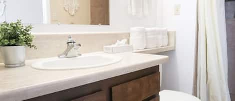 Un baño con lavabo, espejo, toallero y retrete.