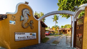 Entrada de un edificio con un letrero que dice "Pousada Cavalinho" y un caballito de mar decorativo.