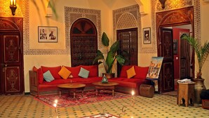 A traditional Moroccan interior with a red sofa, patterned rugs, and ornate wooden doors. - Riad Amiris (Marrakech)