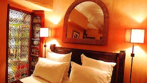 A bedroom with a bed, two bedside lamps, a large mirror, and a decorative iron gate. - Riad Amiris (Marrakech)