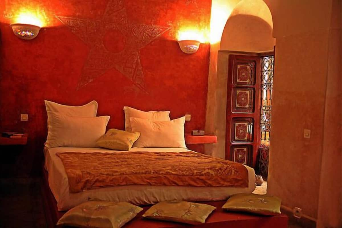A bed with pillows and a blanket, a wall with a star design, and a door with a window.