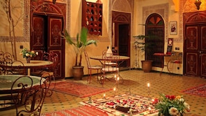 A traditional Moroccan interior with ornate doors, a tiled floor, a central fountain, and a dining area with metal chairs and tables. - Riad Amiris (Marrakech)