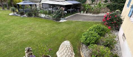 A well-maintained garden with a lawn, potted plants, and a stone sculpture.