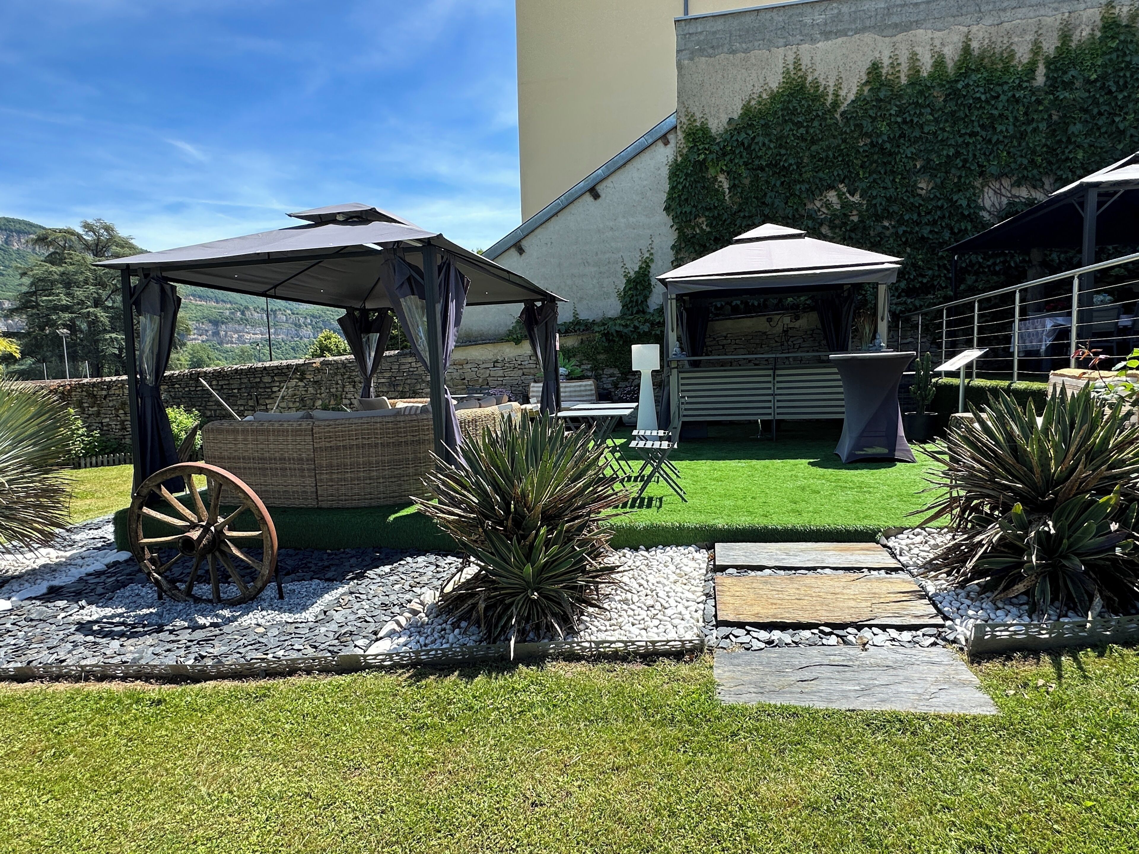 A patio area with outdoor seating, a decorative wheel, and a stone wall.