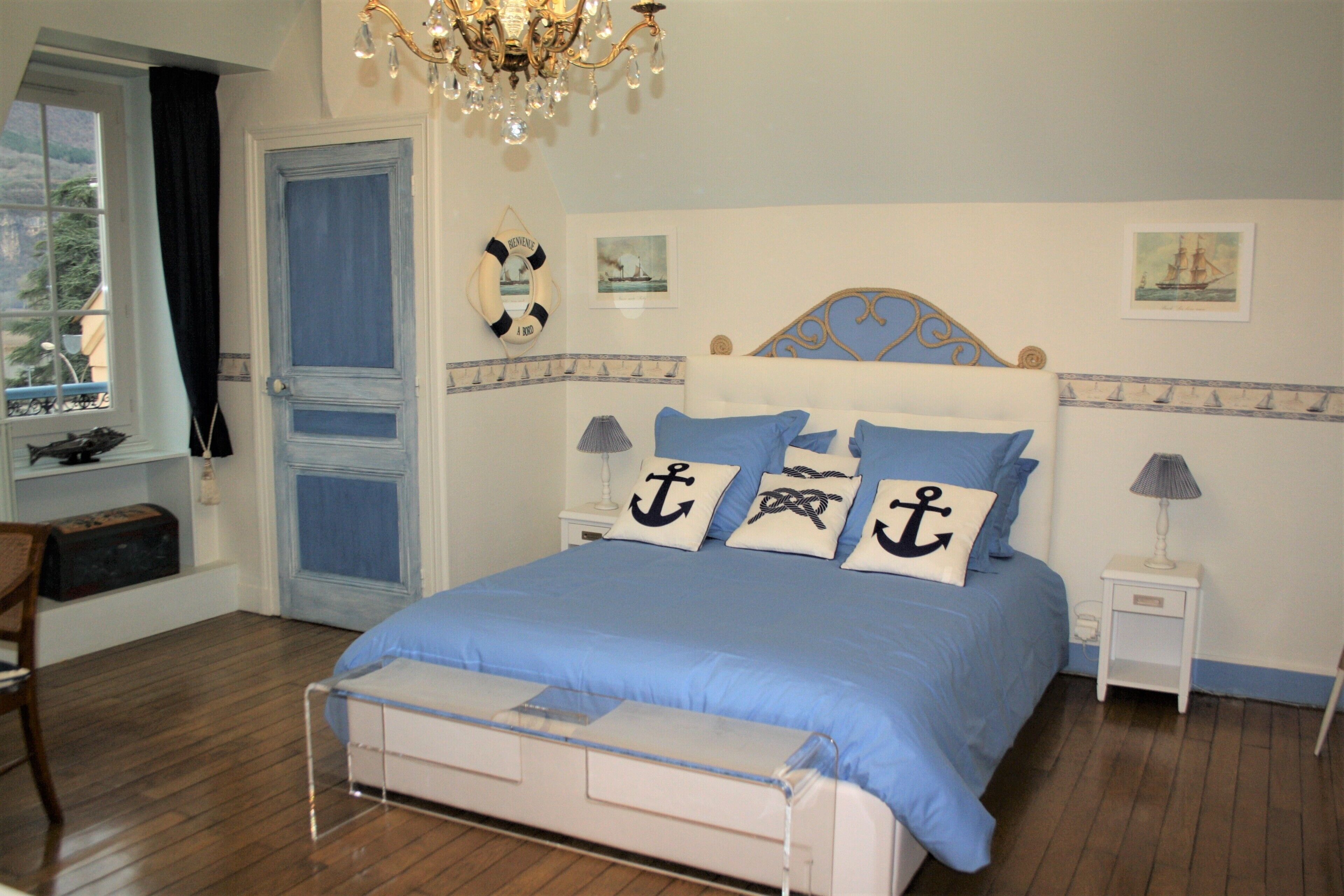 A bedroom with a bed, a nightstand, a chair, a window, and a door.