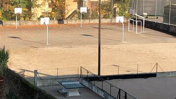 A basketball court with multiple hoops, a stone wall, and a building in the background.