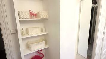 A hallway with white shelves holding baskets and a mirror.