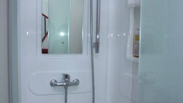 A bathroom with a shower, a mirror, and a soap dispenser.