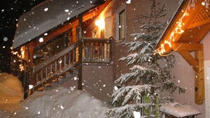 A snow-covered wooden staircase leading to a building with a balcony.
