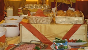 A buffet setup with various food items, including bread, cheese, and meats, arranged on tables with striped cushions.