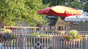 A wooden fence with flower planters and a red umbrella.
