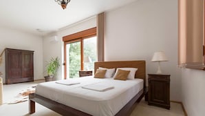 A spacious bedroom with a large bed, a wooden wardrobe, a potted plant, and a view of greenery outside. - The Belgrade Hills (Belgrade)